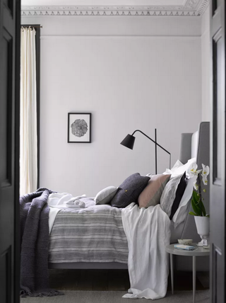 A muted gray bedroom scheme with white, blush and navy soft furnishings and black metal lighting