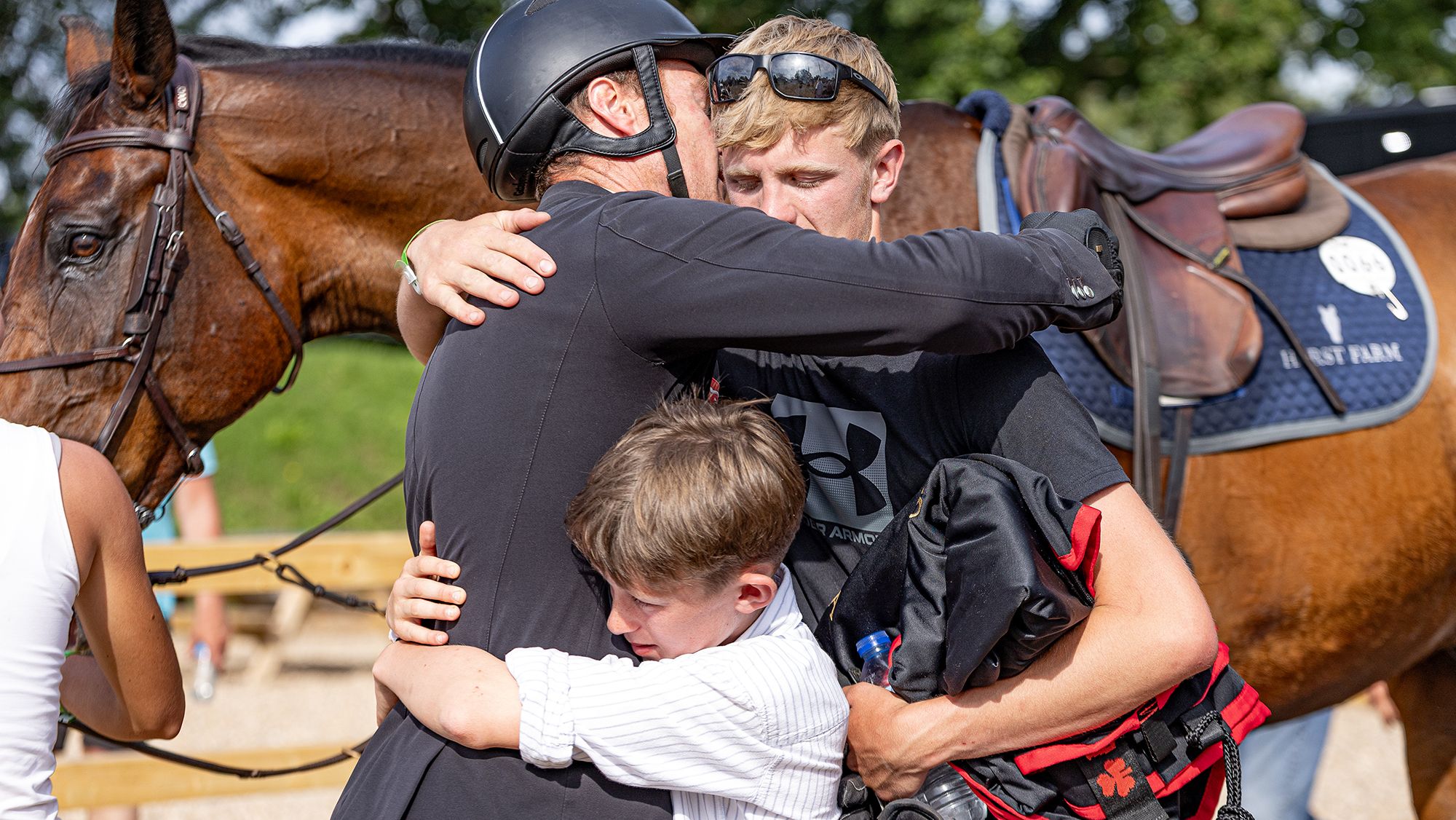 William Whitaker, son Oliver and groom Lewis Robert Shaw share a moment after winning the Hickstead Derby.