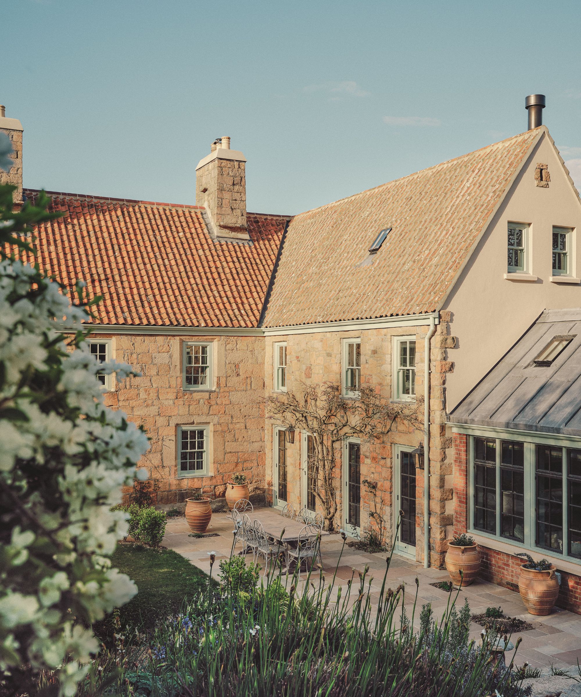 Exterior of a yellow stone cottage with pale green windows