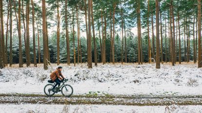 Image shows cyclist riding through the snow with Christmas gifts
