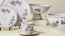 Blue and white floral dinner plates, serve bowls and teacups against a cream background