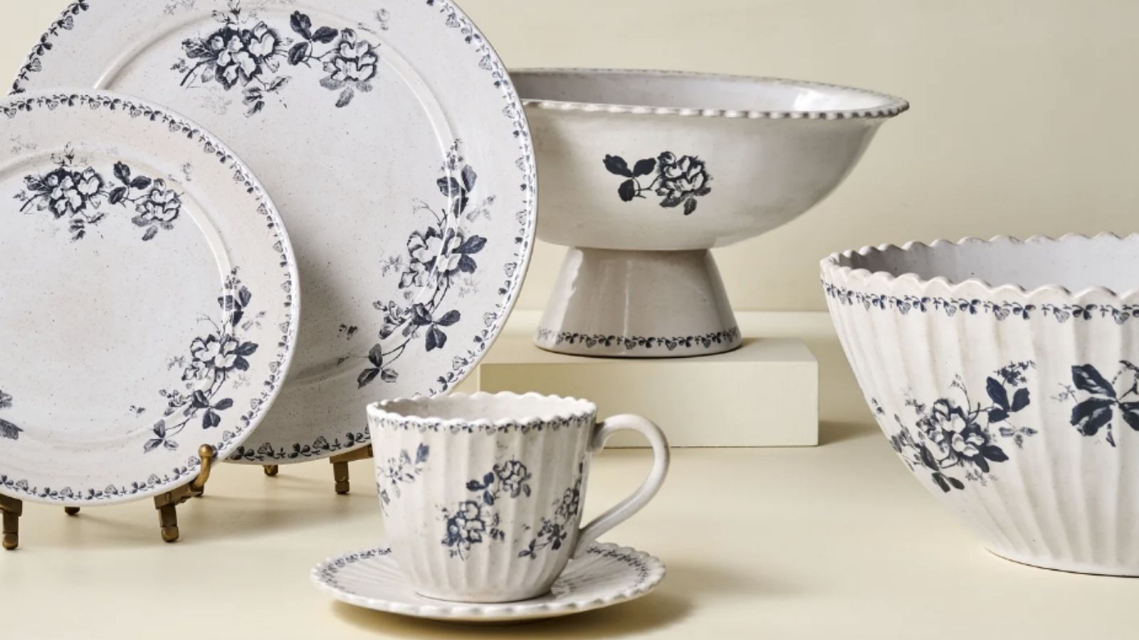 Blue and white floral dinner plates, serve bowls and teacups against a cream background