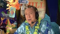 Wheel of Fortune announcer Jim Thornton sitting in booth behind microphone wearing Hawaiian shirt and leis