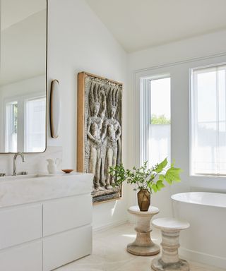 bathroom white walls relief sculptural artwork and two pedestal stools