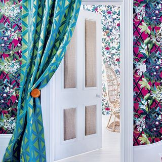 floral room wallpaper with blue curtains and white door