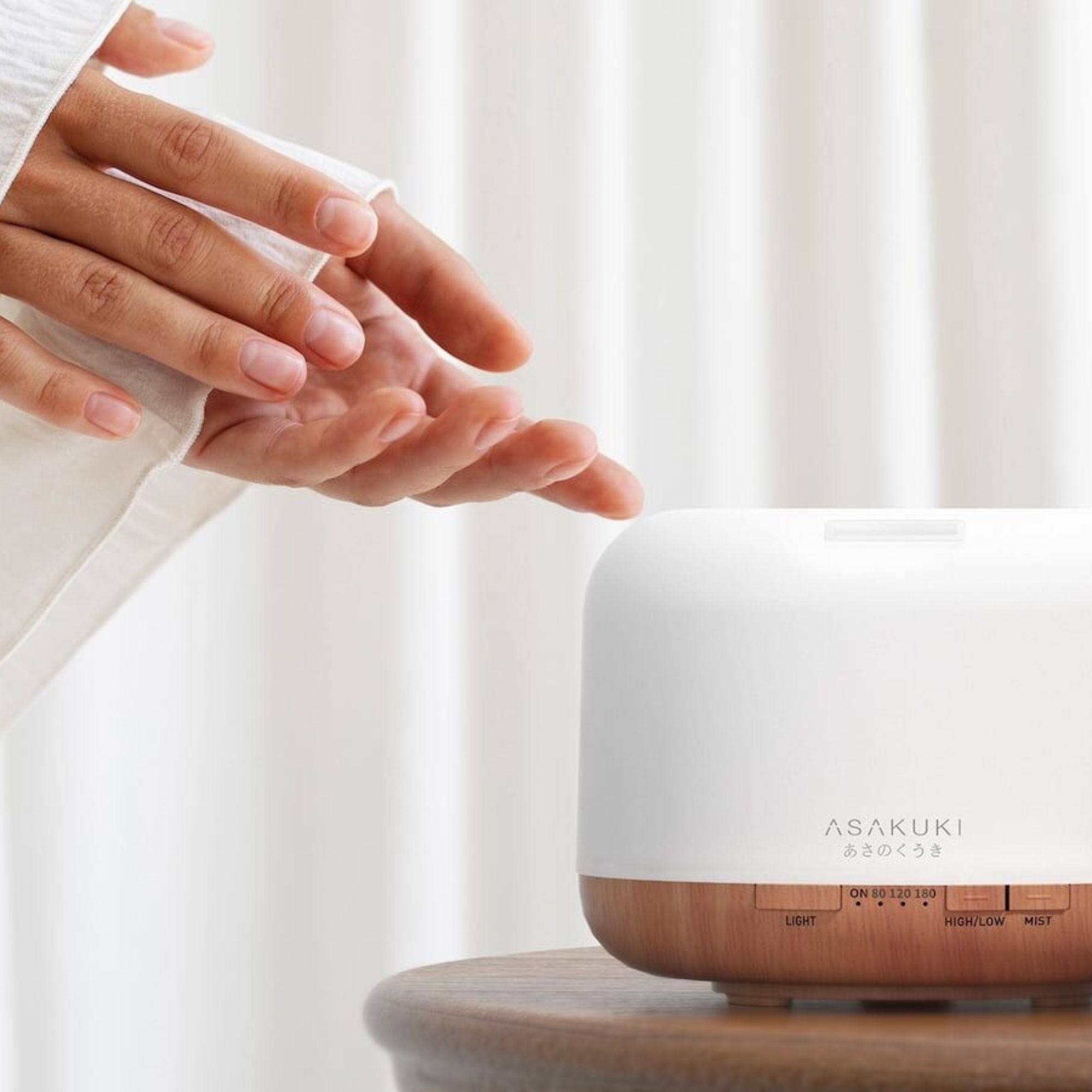 A hand switching on the ASAKUKI Portable Essential Oil Diffuser.