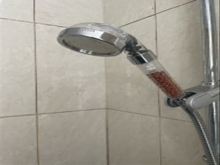 The head is installed to a shower hose in a white porcelain bathroom