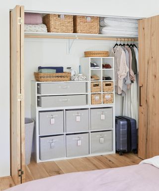 Walk in closet with freestanding drawer unit, laden with woven baskets