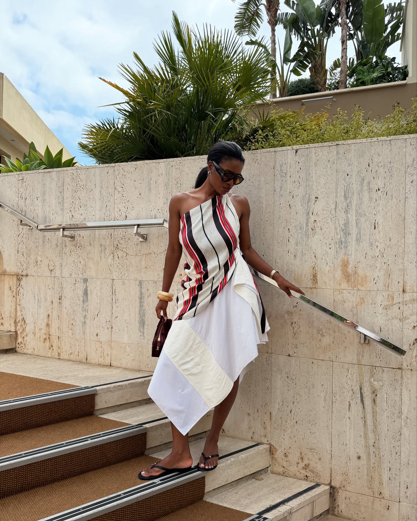 Woman in stripe top, white skirt, and black flip-flops