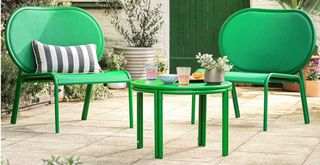 close up shot of generously sized green garden chairs and a matching coffee table in a garden