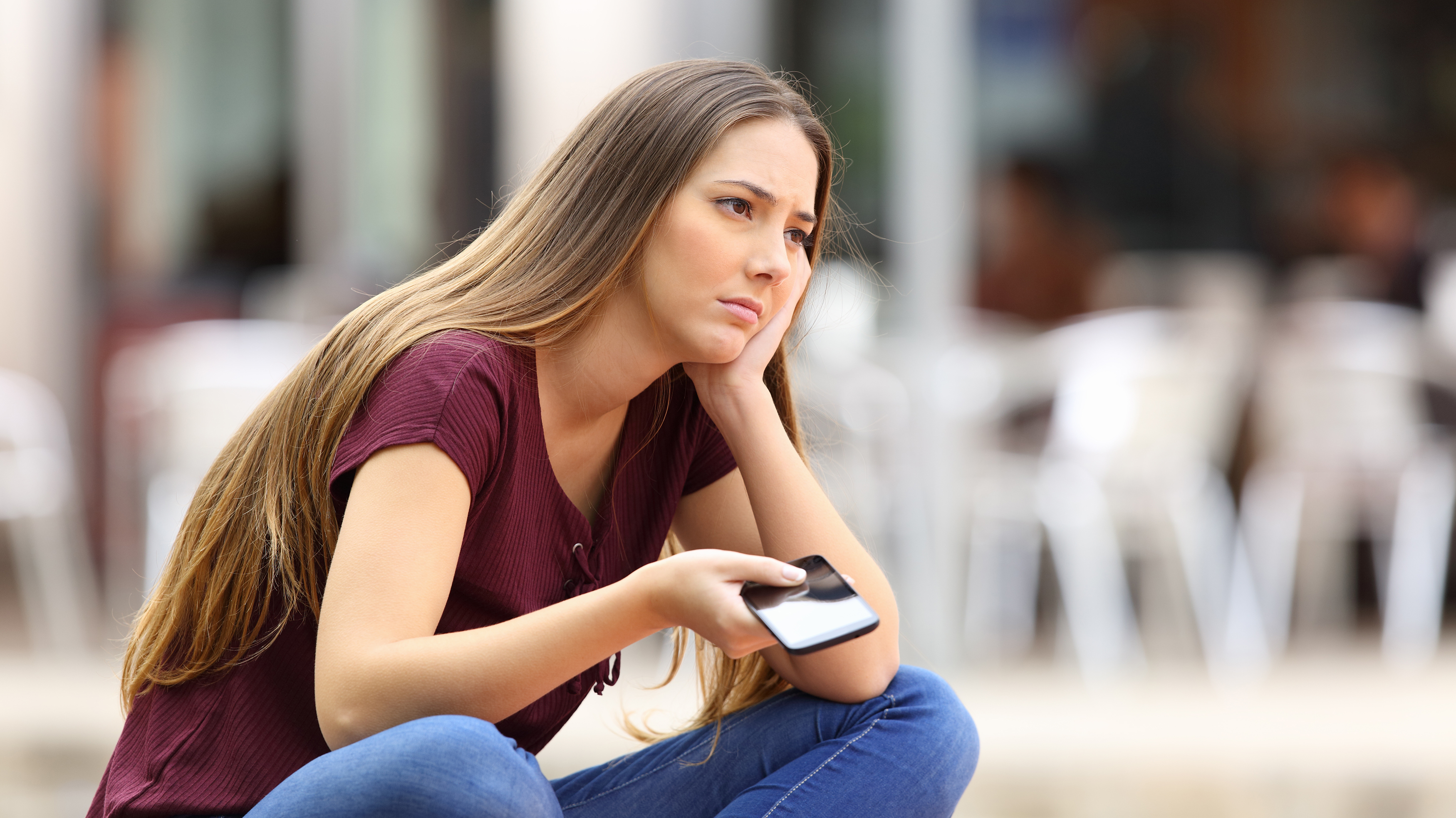 A sad girl waiting for a mobile phone call or message