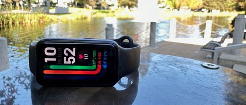 The Amazfit Band 7 sitting in front of a fountain, showing daily workout stats on the watch face.