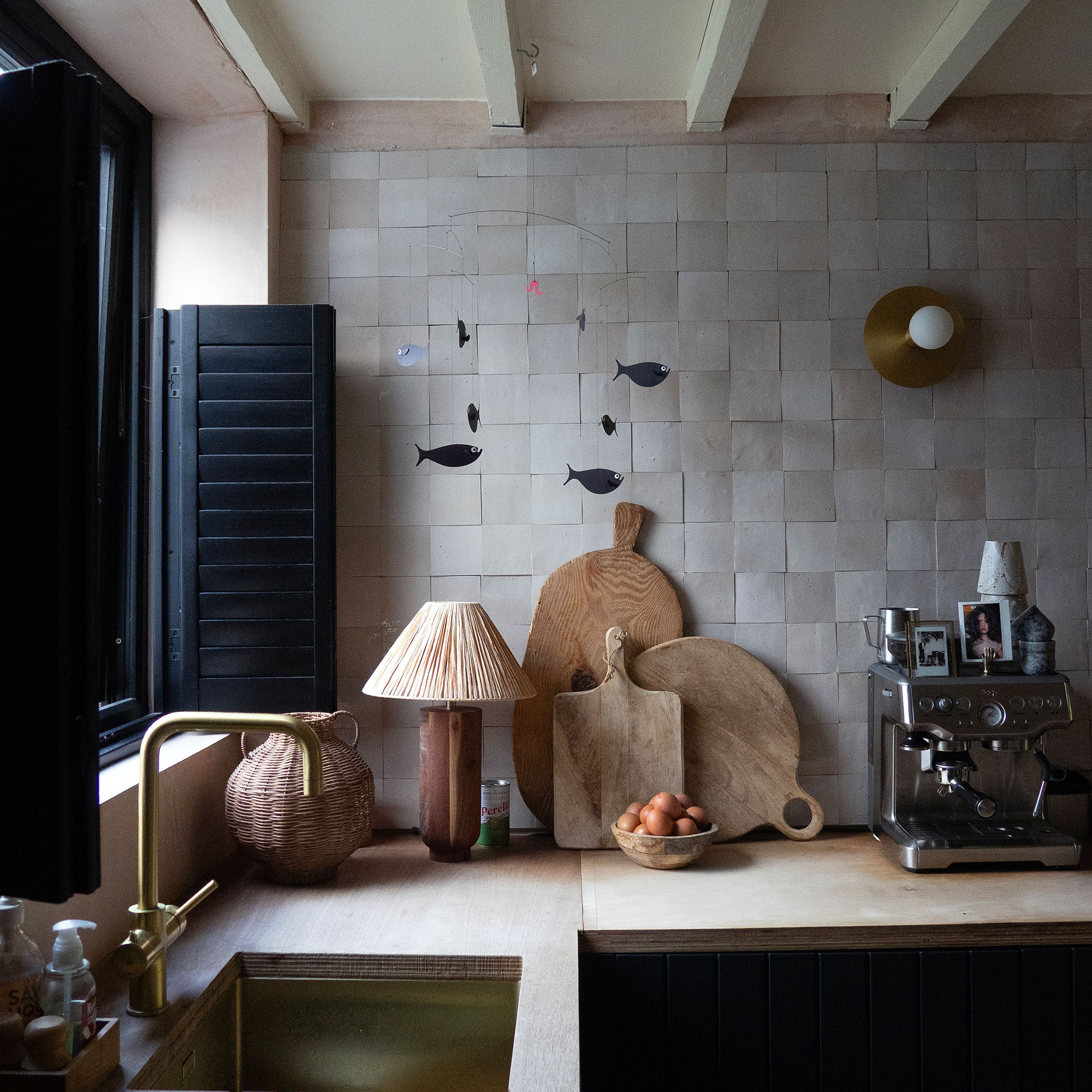 Kitchen with tiled walls, wooden boards, wall light and black shutters