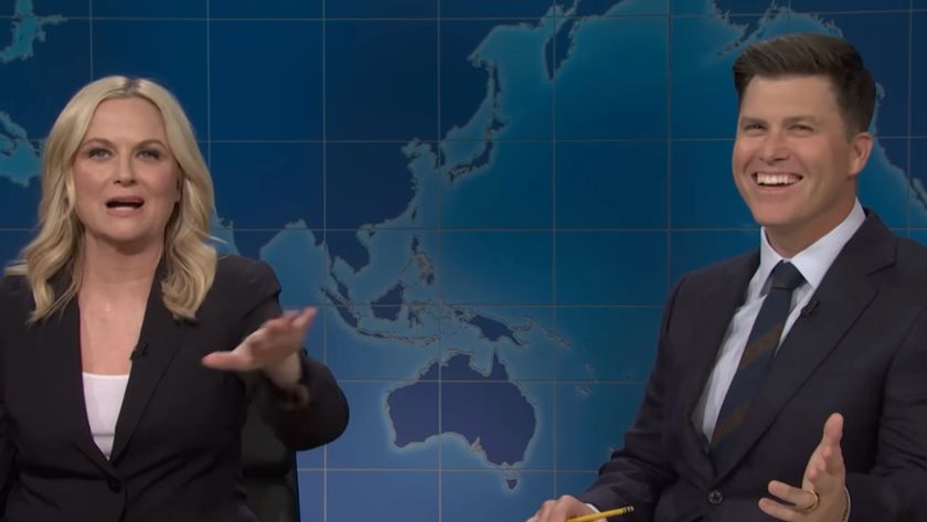 Colin Jost laughs while Amy Poehler makes a joke on Weekend Update.