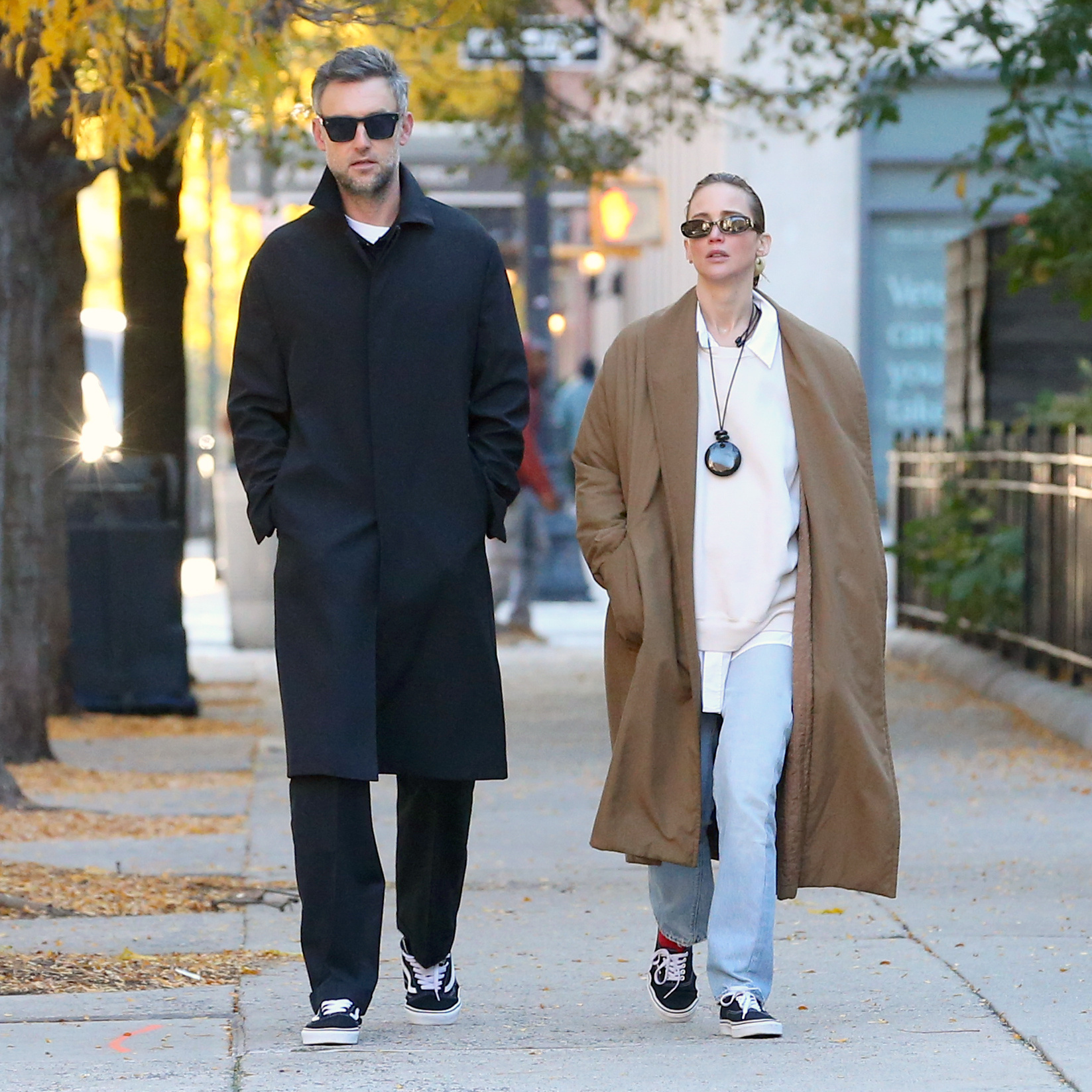 Jennifer Lawrence wore a button-down, a crewneck sweater, a wool jacket, and jeans with black-and-white Vans sneakers