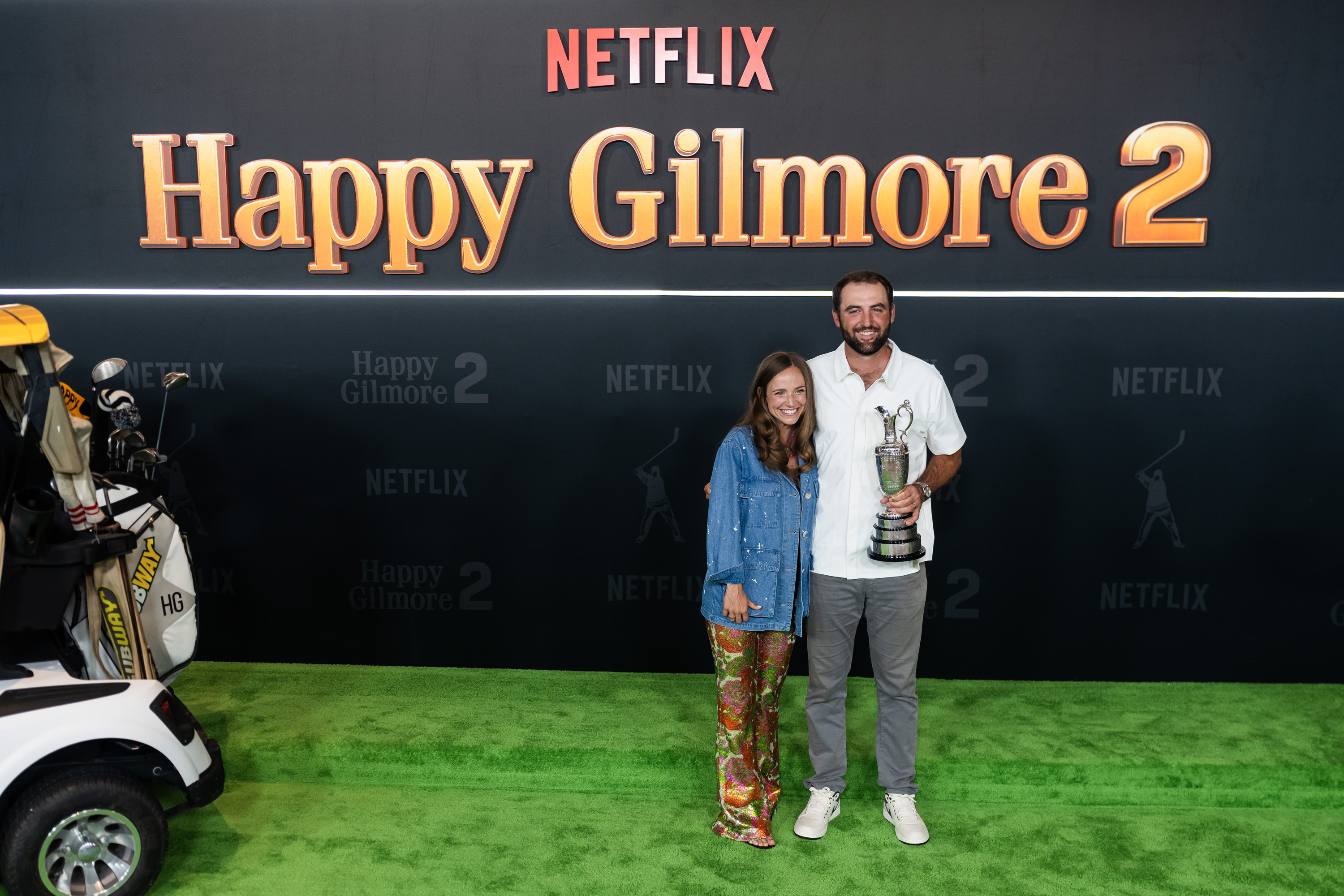 Scottie Scheffler and wife, Meredith pose with the Claret Jug at the premiere of Happy Gilmore 2 in New York