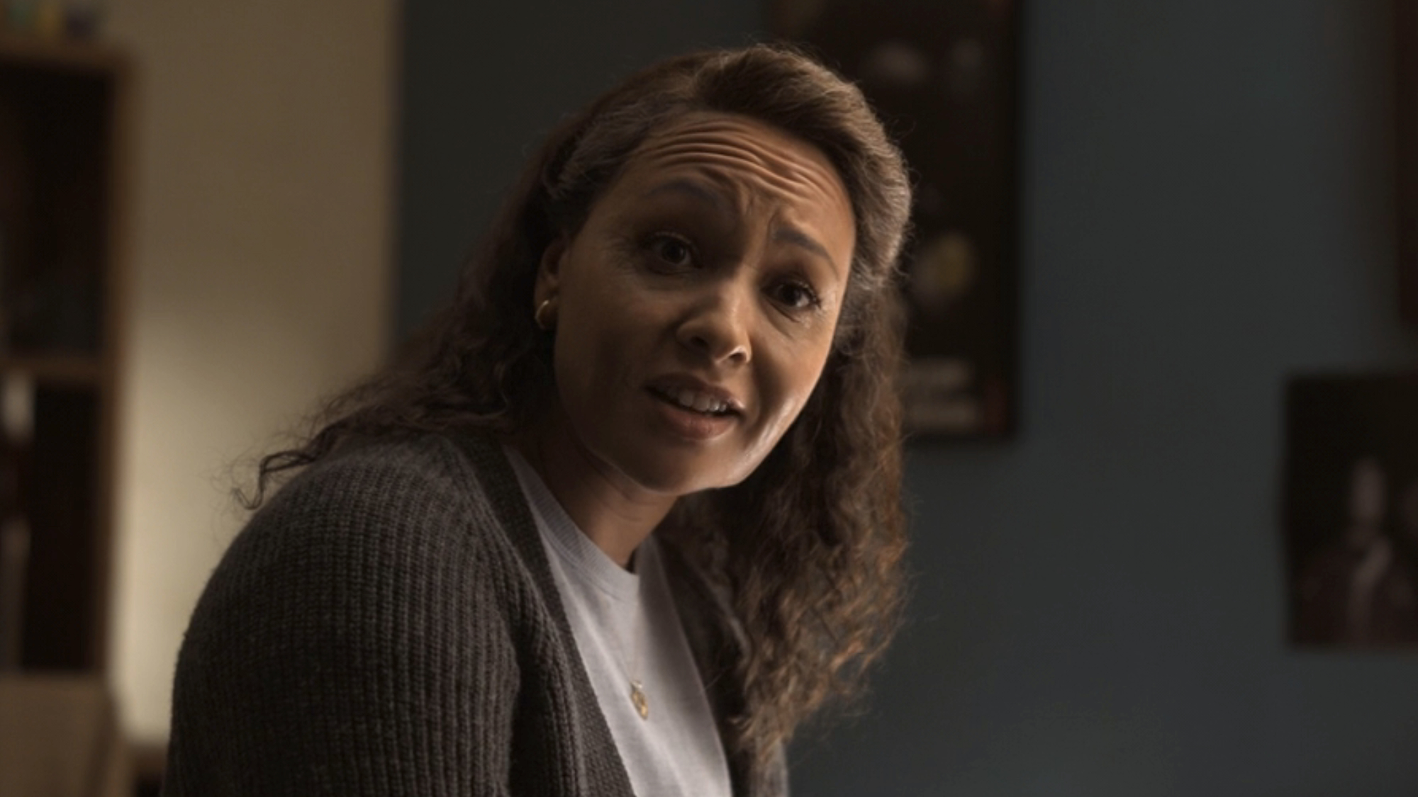 Jasmine Cephas Jones' Bernadette Stewart wearing dark gray sweater over a lighter shirt, talking to John about his future in Lanterns.