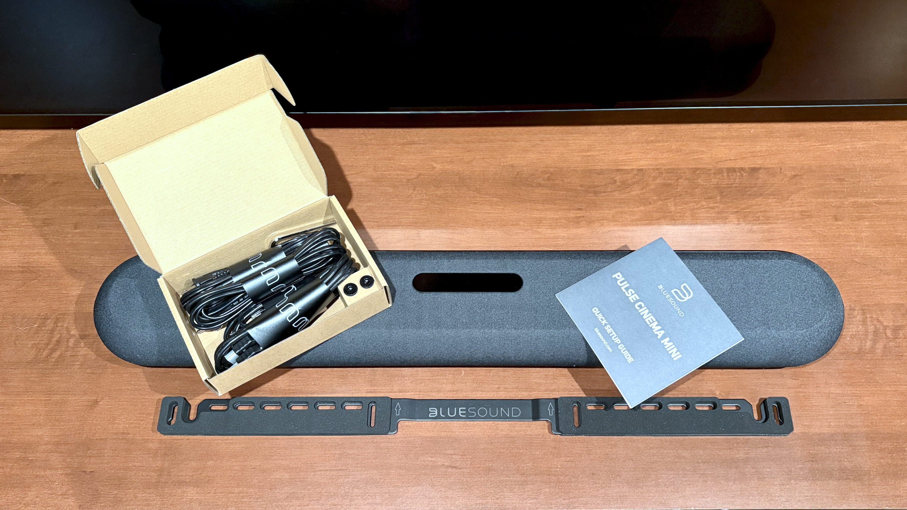The Bluesound Pulse Mini soundbar pictured with included cables and guidebook