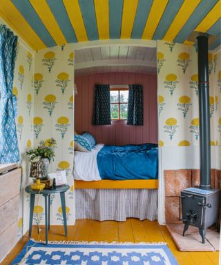 Shepherds hut decorated with Molly Mahon wallpaper with a striped yellow and blue ceiling, photograph Sarah Weal