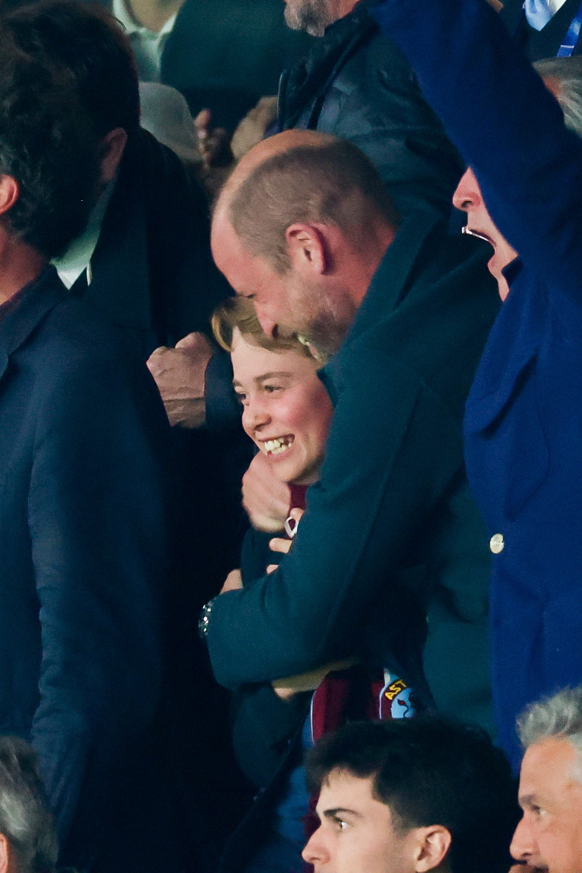 Prince William hugging Prince George at a soccer match and smiling
