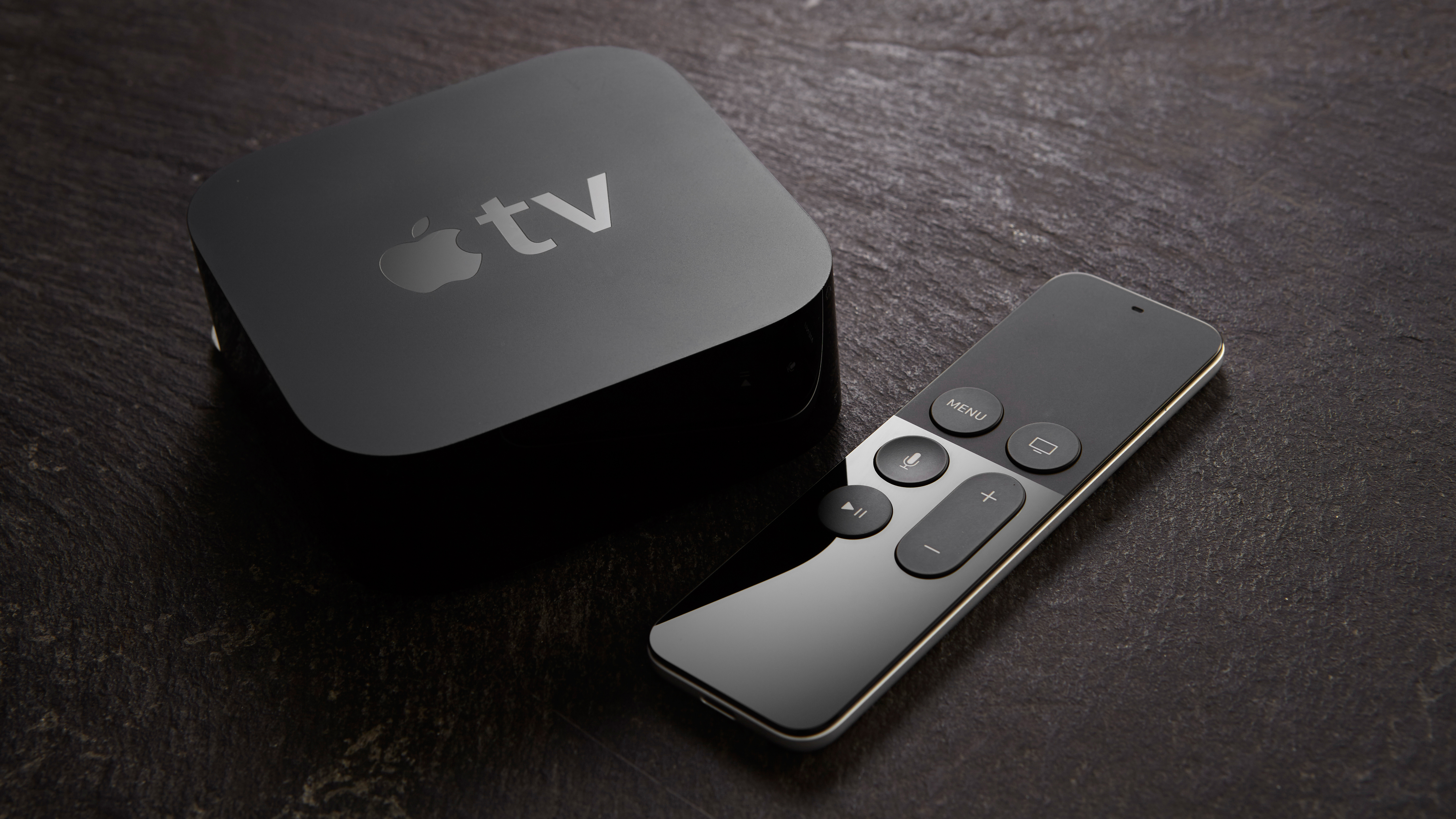 An Apple TV next to the Siri Remote on a table