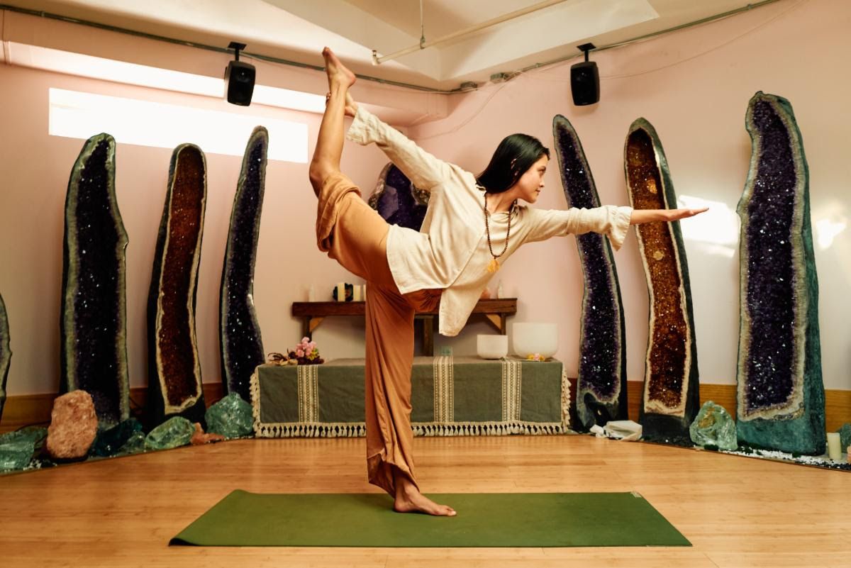 A woman does yoga in a &quot;Wellness Womb&quot; in front of brightly colored geodes and crystals with a Genelec sound system providing soothing sounds. 