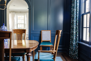 A room fully drenched in blue with a wooden dining table and chairs