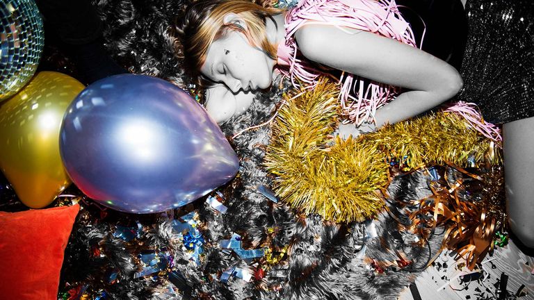 Woman lying asleep on the floor with party balloons