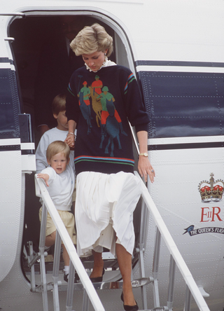 Princess Diana Leaving A Plane At Aberdeen Airport With Prince Harry At The Start Of Their Annual Holiday In Scotland. Her Jumper Has A Motif Of A Polo Player in 1986