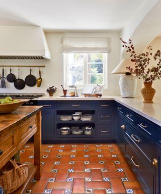 kitchen with terracotta tiles and dark blue cabinets and wood island