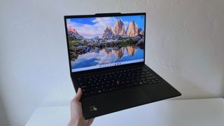 Someone holding the Lenovo ThinkPad T14s Gen 6 in front of a white table