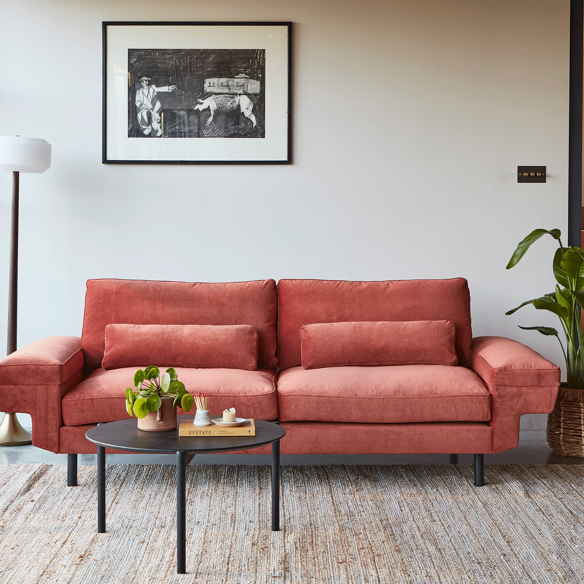 Terracotta sofa in a white room with black and white photo on wall
