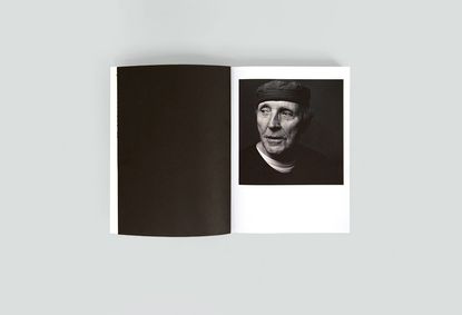 An open book with a plain black page on the left and a portrait of a man on the right