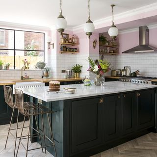 kitchen with pink wall and two chairs with kitchen counter