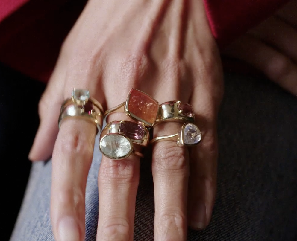 a close-up image of Larissa Mills wearing a stack of silver and gold rings