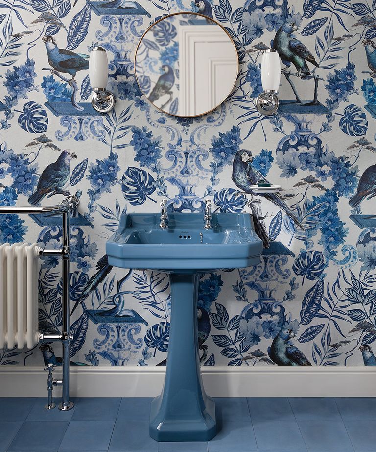 A Burlington bathrooms design showing a blue sink in front of blue floral motif wallpaper and a circular mirror