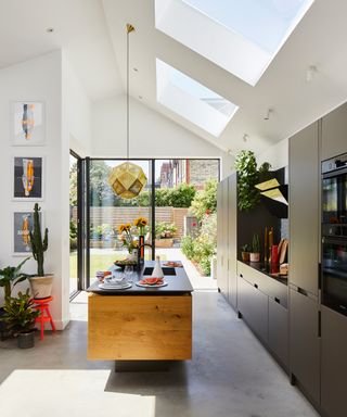 A pitched roof kitchen extension with a central wooden island and black cabinetry