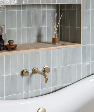 A sophisticated bathroom featuring a recessed shelf built into a wall of glazed green tiles.