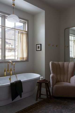 grey bathroom with free standing bath and a grey armchair