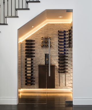 A contemporary staircase wine cellar with glass doors and backlighting