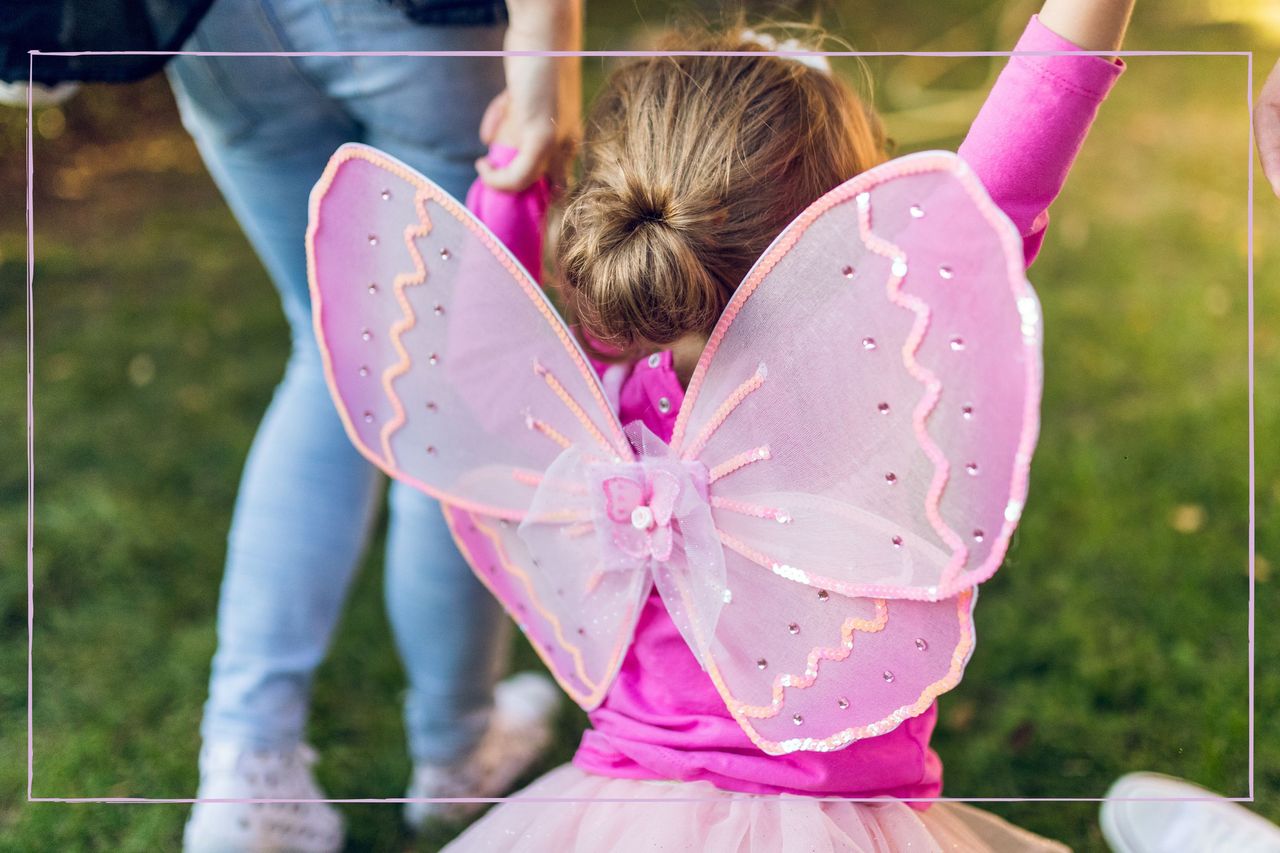 Little girl dressed as a fairy holding her parents&#039; hands