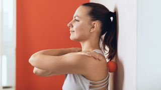 woman using a massage ball on her back