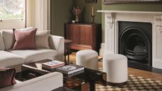 a green living room with white sofas, poufs and checkerboard rugs, with a large white fireplace