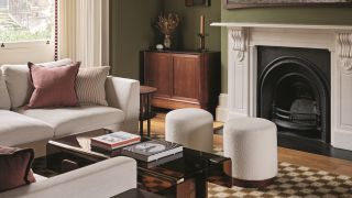 a green living room with white sofas, poufs and checkerboard rugs, with a large white fireplace