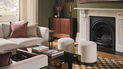 a green living room with white sofas, poufs and checkerboard rugs, with a large white fireplace