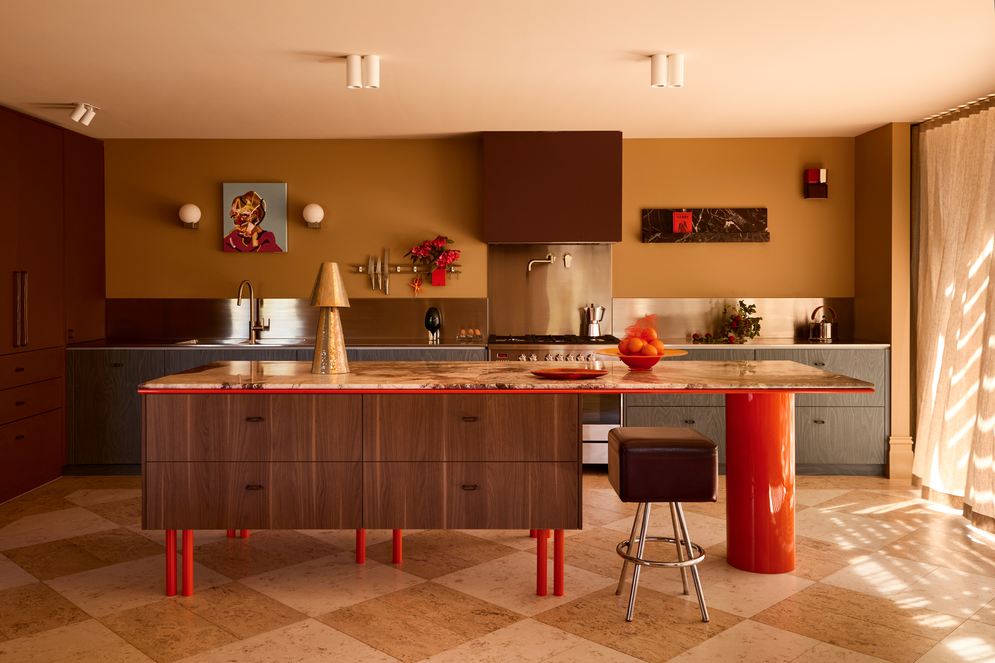 a warm-toned kitchen with a walnut island bench and red details