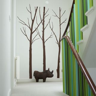 hallway with banisters painted greens woodland themed mural in the landing space