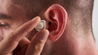 A man places an earplug into his ear