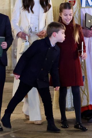 Prince Louis blowing out Princess Charlotte's candle during a carol service