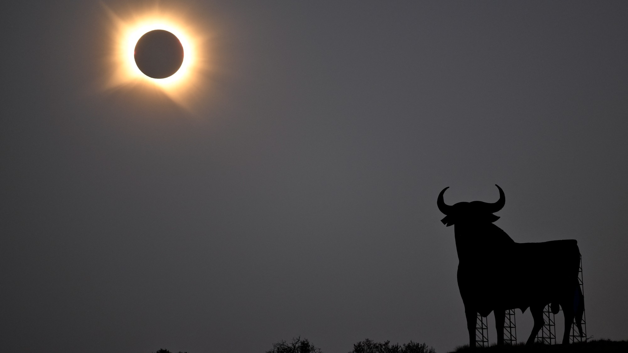 the moon completely blocks the sun, creating a fiery ring in a grey sky